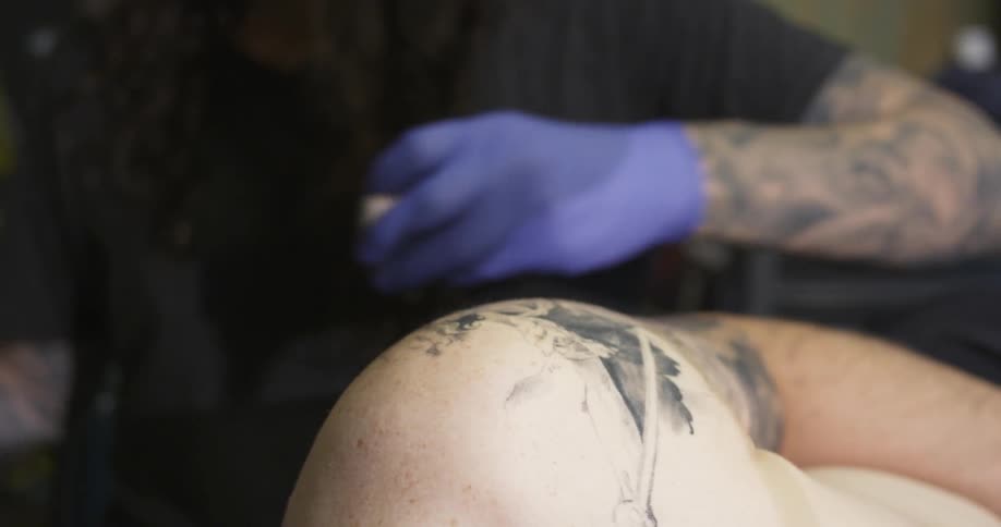 A man gives someone a tattoo on their bicep