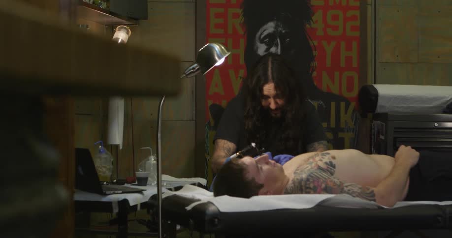 A tattoo artist works on a male customer