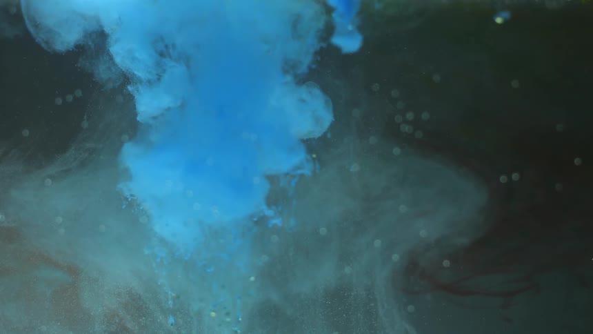 A blue substance drops into a liquid and disburses