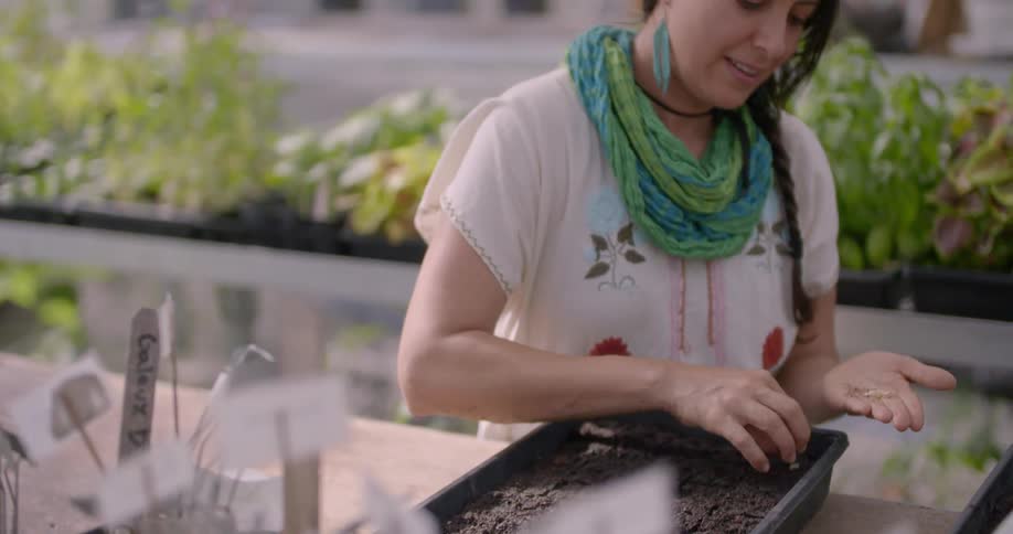 A woman is planting seeds in a large pot