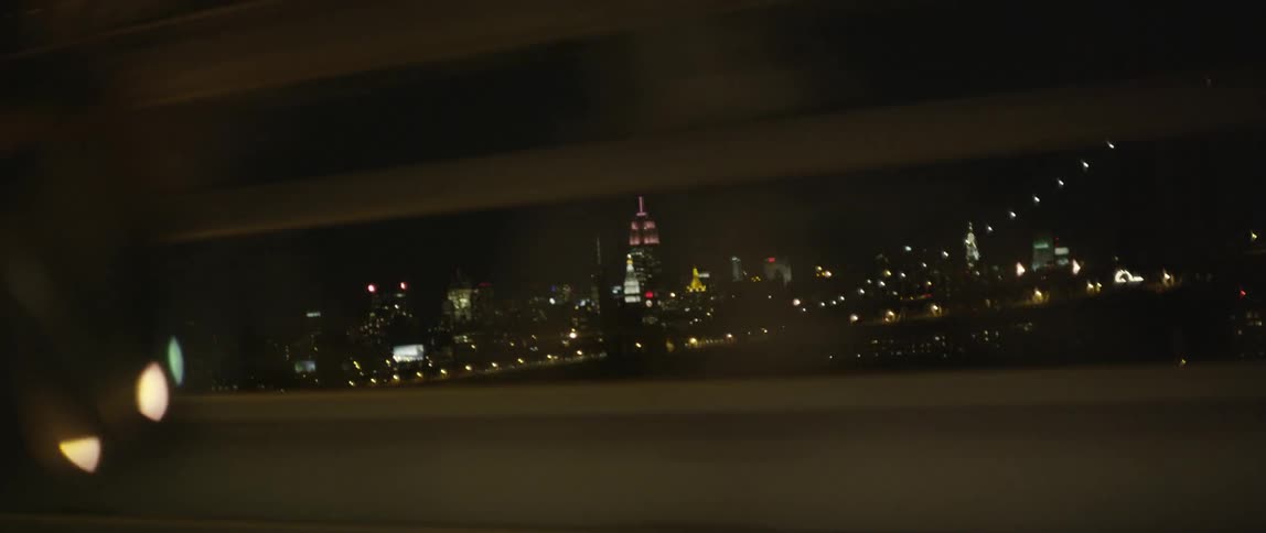 A city skyline passes outside the window of a vehicle
