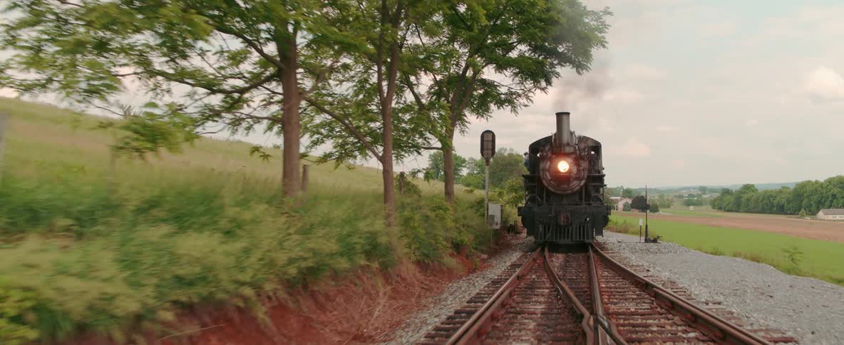 A coal burning train is traveling backwards down a track