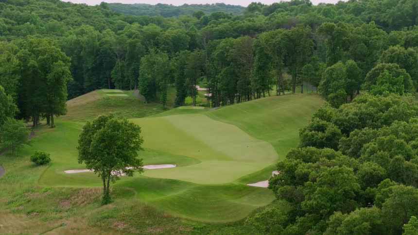 The golf course has many trees and hills