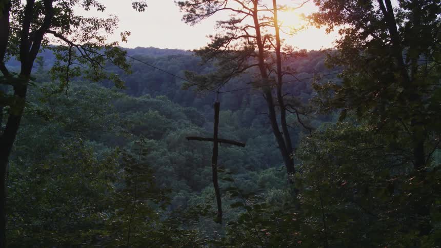 Cross hangs from a wire under a bright sun