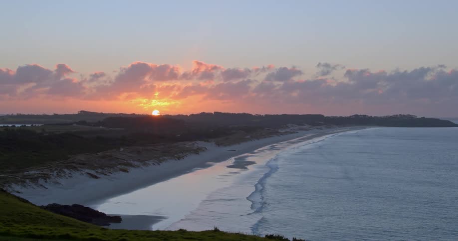 The sun sets behind a beach