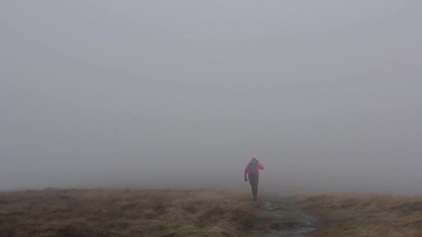 A person walks along a path in the fog