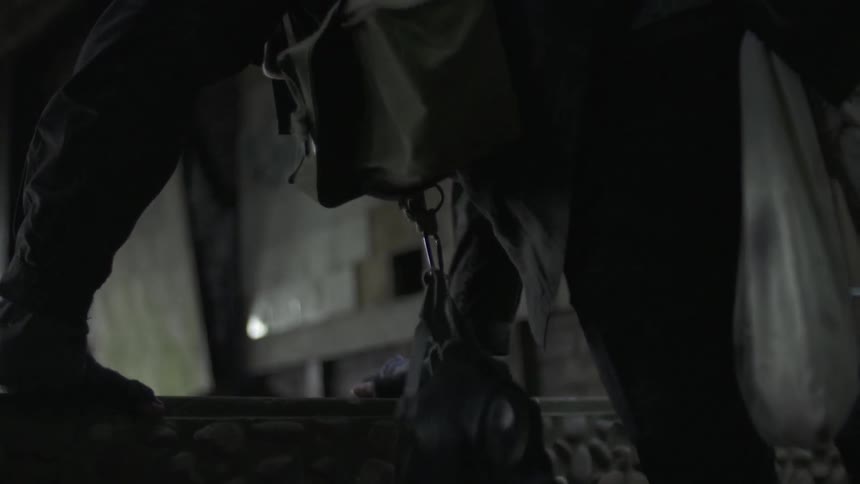 Person wearing lots of equipment climbs into abandoned structure