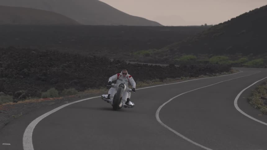 Motorcyclist rides on a rural road at sunset