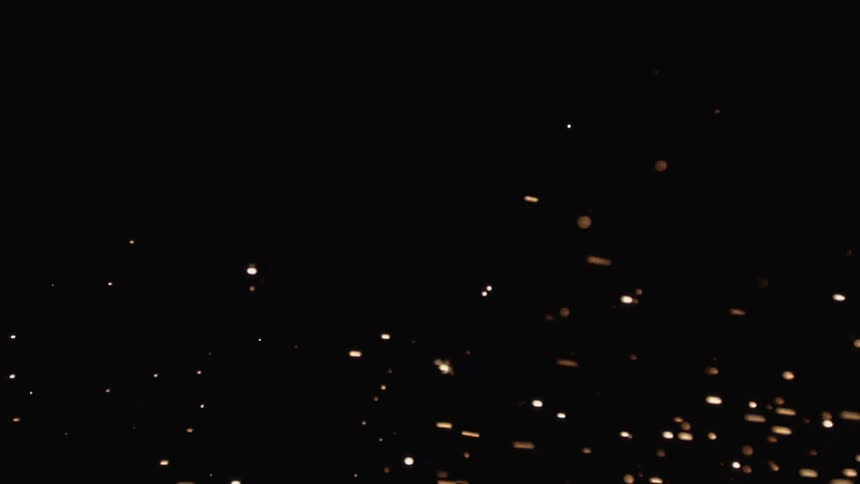 Orange and white sparks floating in a dark room