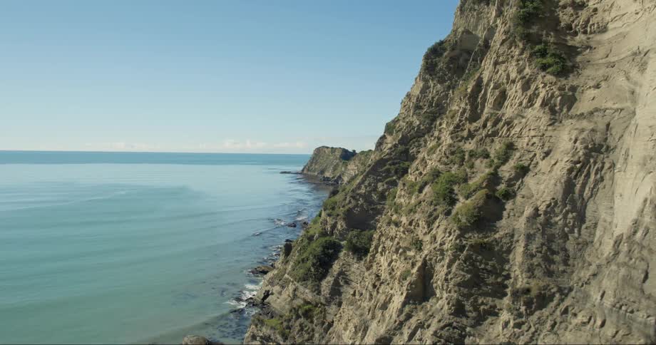 The cliff has many jagged rocks towards the water below