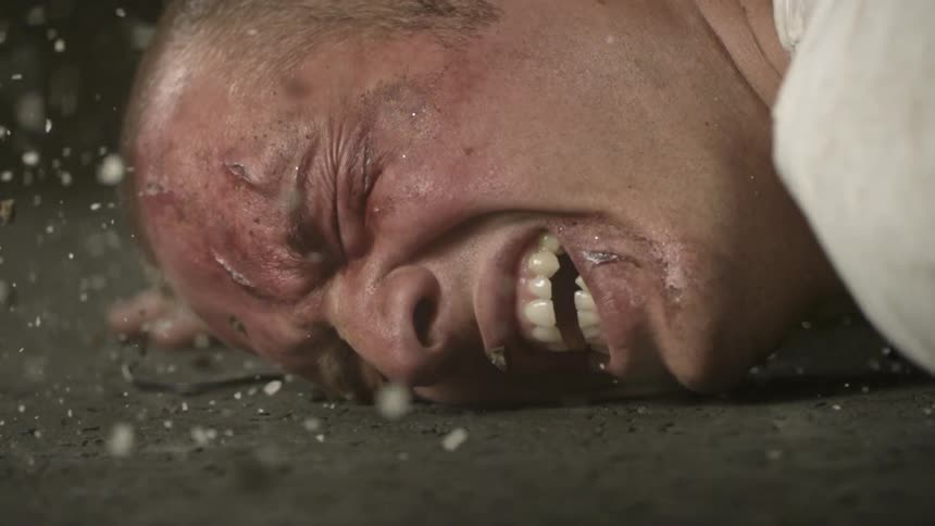 A man is being hit with debris while he is in pain on the ground