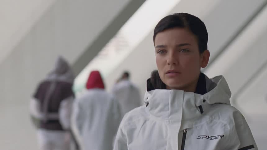 A woman in a white suit is walking through a corridor