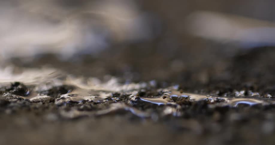 A person scrapes the top of the mud