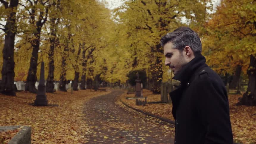 A man is walking through a cemetery in autumn
