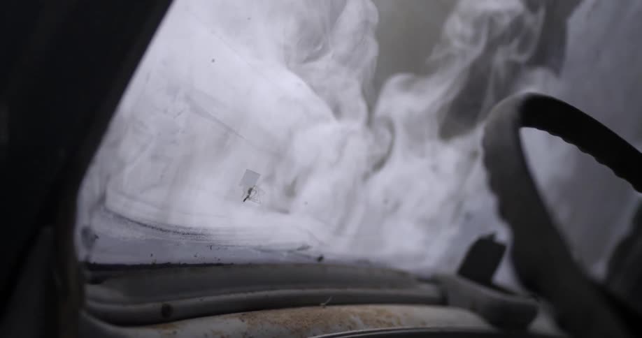Smoke is rising up from a broken old car