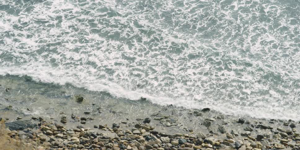 Ocean waves wash ashore a rocky beach