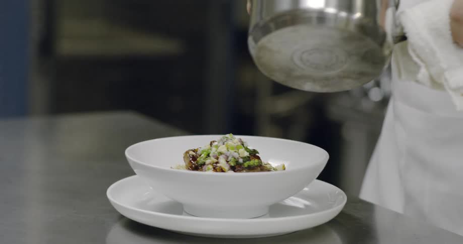 Chef plates food in a kitchen