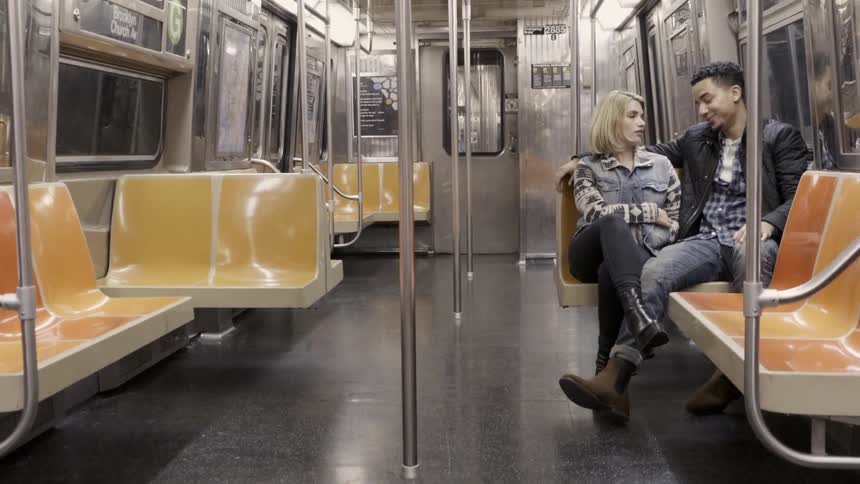 Couple sits talking on a subway