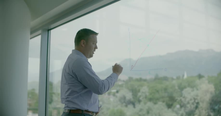 An instructor is using a marker to write on a window in a classroom