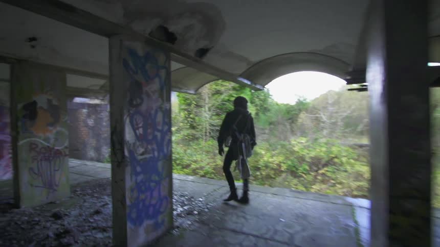 A woman is walking under a bridge