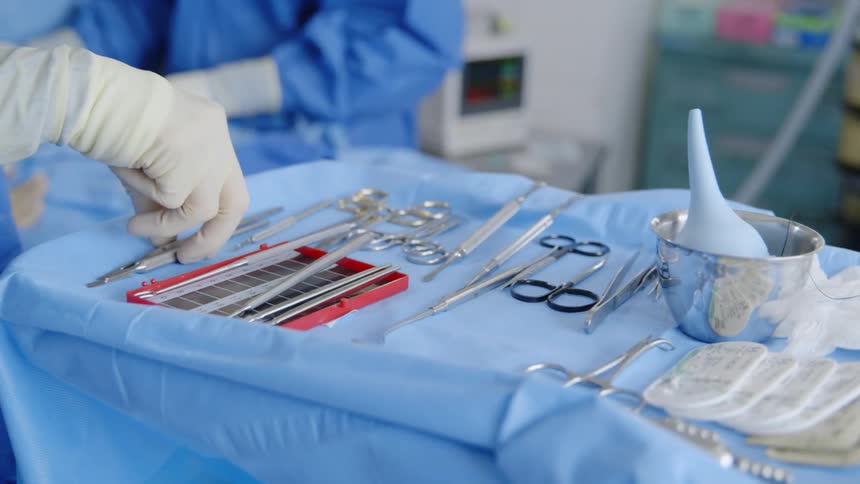 A surgeon organizes tools on a surgical tray
