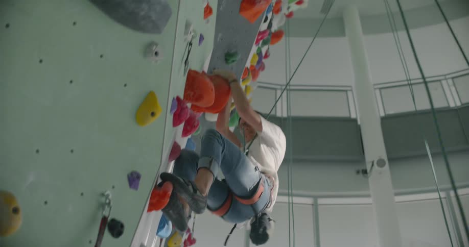 A man climbs up a rock climbing wall