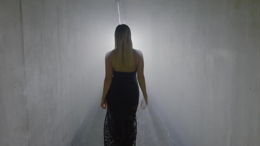 A woman is walking in a tunnel toward a light