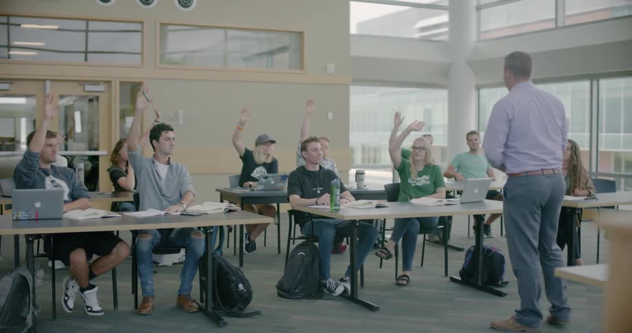 Students raise their hands in a classroom