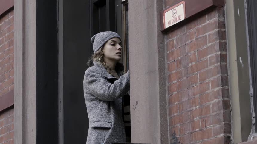 Woman walks on a city street and approaches a door