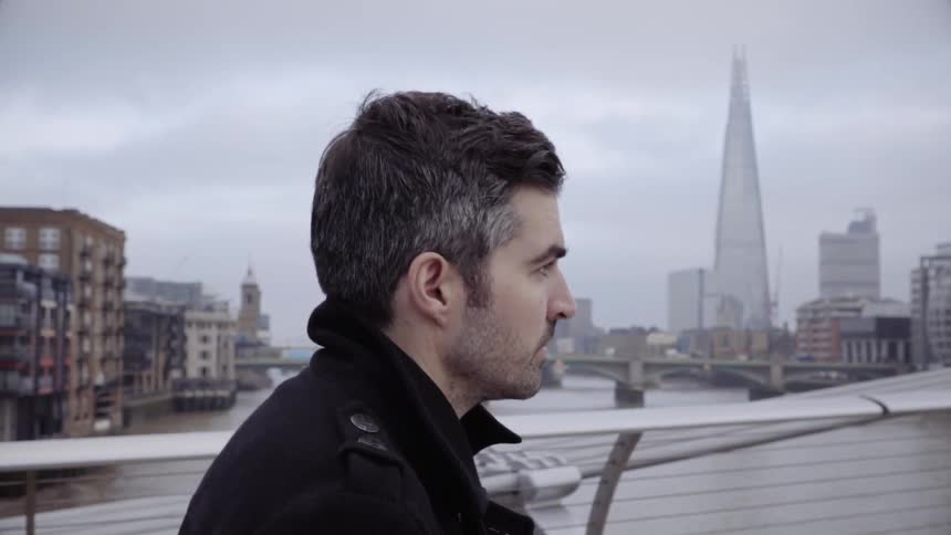 Man walks over a bridge in a city