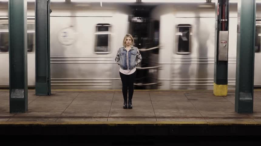 Woman stands in front of a moving subway train
