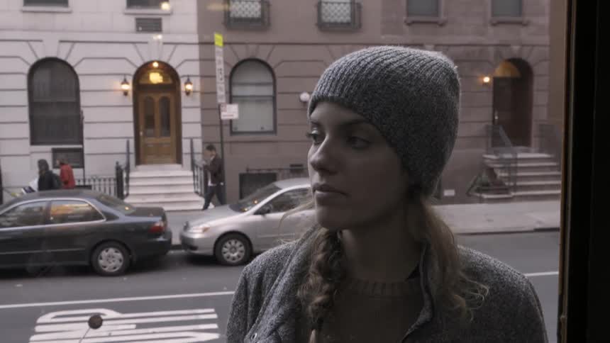 A woman is walking up some stairs and rings the bell of a door