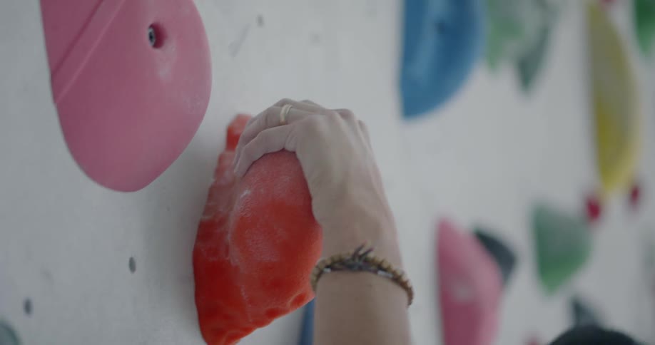 A man is climbing up a rock climbing wall in a gym