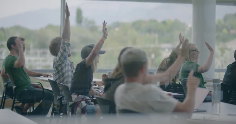 Students in an adult class raise their hands in response to a teacher