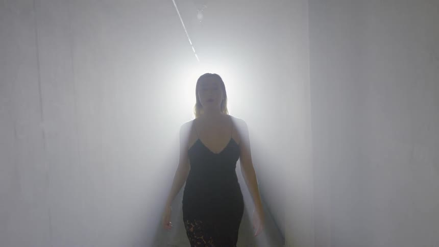 A woman walks in a brightly lit hallway