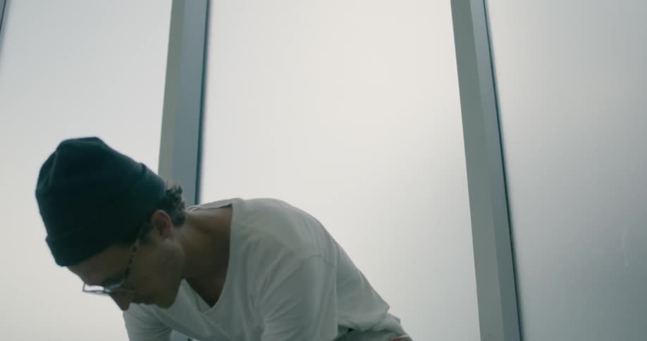 A man is crouched down by the glass window
