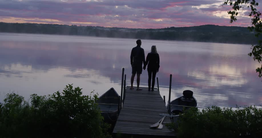 A man and woman hold hands on a dock