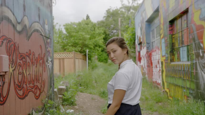 Woman walking outside in between buildings covered in graffiti