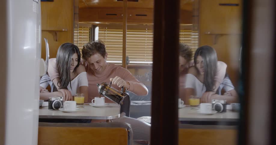 A man and woman sit close together pouring coffee