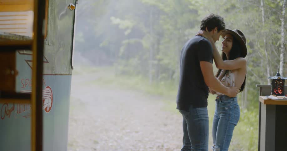Man and woman embrace near a forest