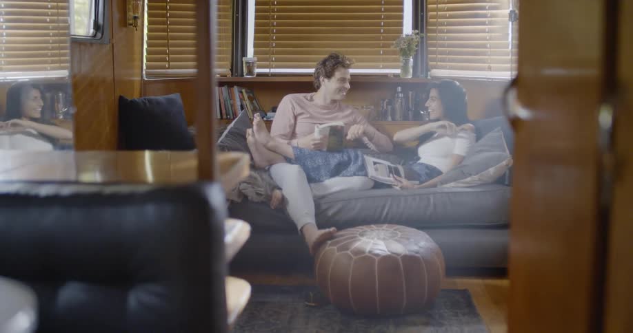 A man and woman talk and read together on the couch