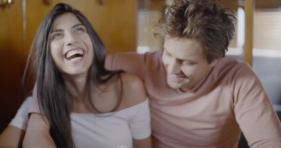 A man and a woman are sitting together playing cards and laughing