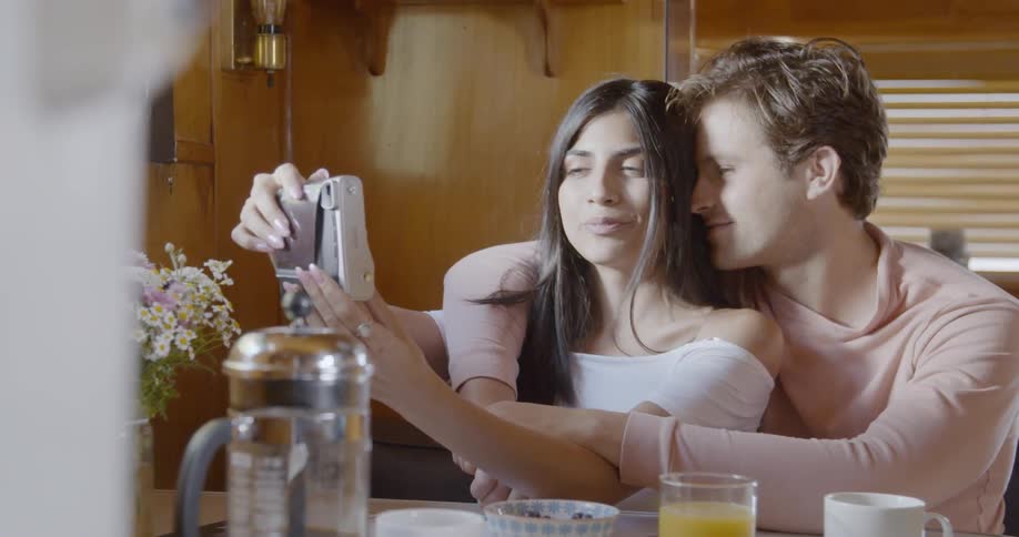 Man and woman take picture of themselves sitting at a table