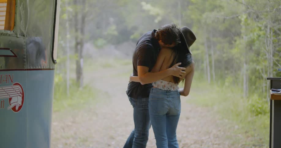 A man kisses a woman standing on a trail near a foggy forest