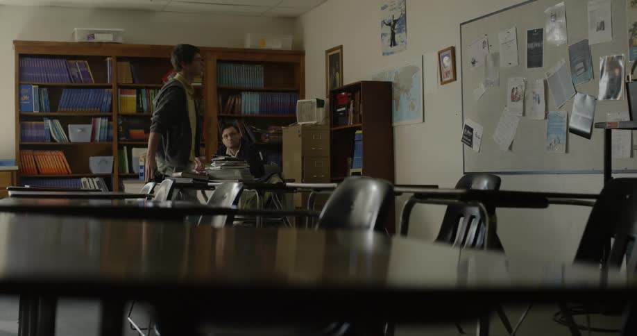 Two people are sitting in a classroom doing work