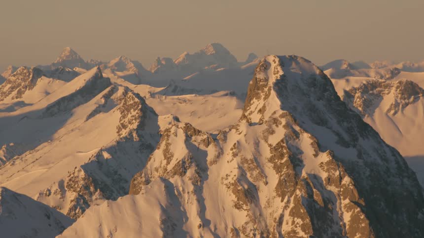 A haze is settling over a snow covered mountain range at dusk