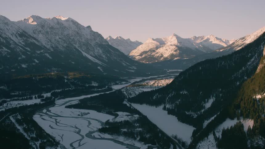 A melting river winds its way through a mountain valley