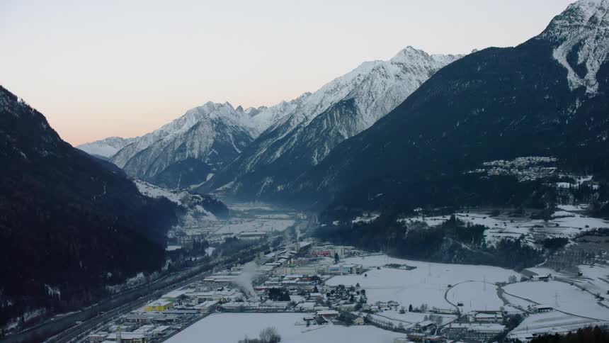 A small snow covered village sits at the foot of a mountain
