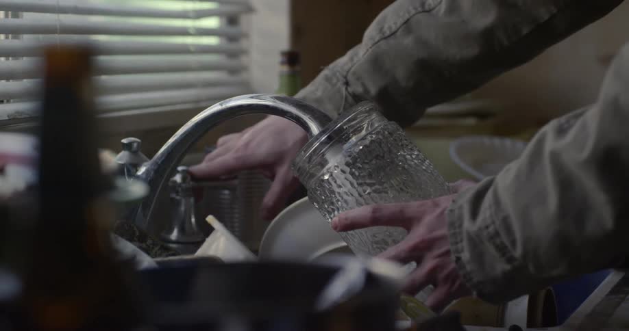 A man gets water from a kitchen tap and drinks from it