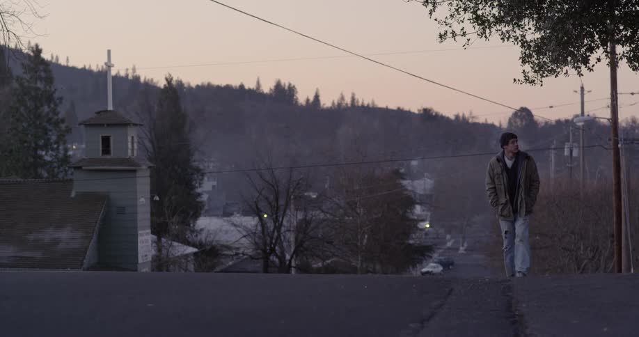 A man walks uphill in the street at sunrise